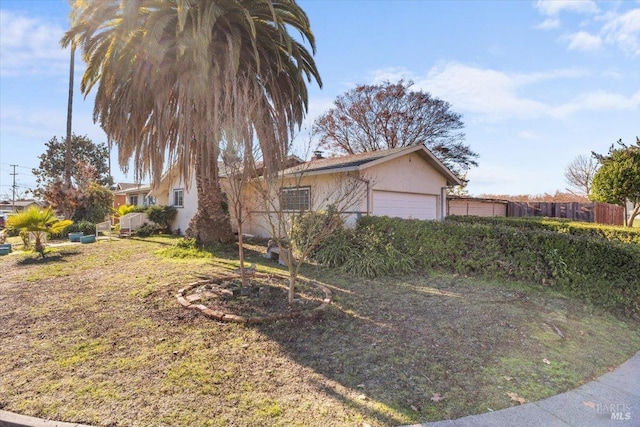 view of property exterior with stucco siding, a garage, and fence