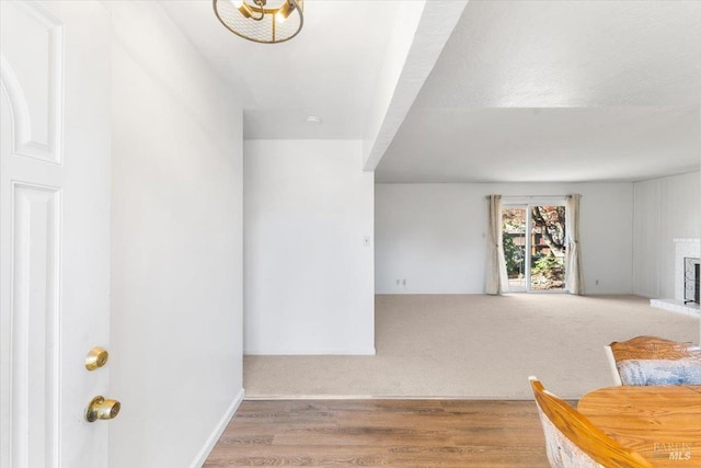 interior space with baseboards, a brick fireplace, and light wood-style flooring