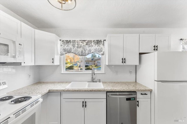 kitchen with backsplash, white cabinets, a sink, and white appliances