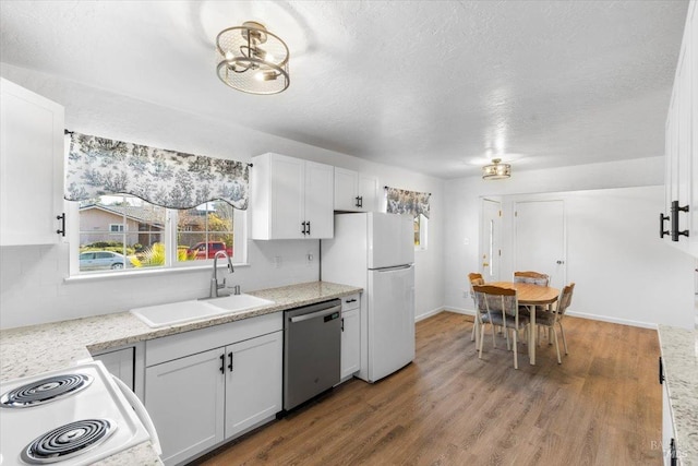 kitchen with white cabinets, a sink, wood finished floors, and white appliances