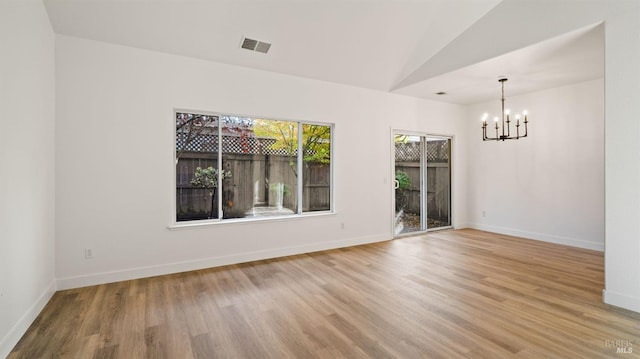 unfurnished room featuring light hardwood / wood-style flooring, lofted ceiling, and a notable chandelier