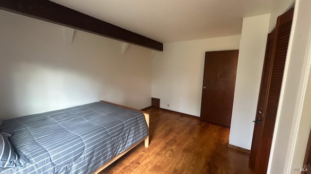 unfurnished bedroom featuring beamed ceiling and dark hardwood / wood-style flooring