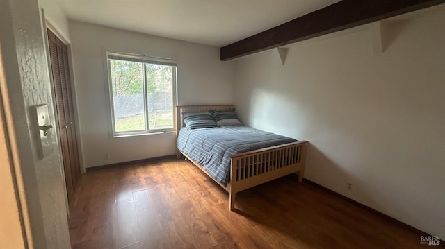 unfurnished bedroom featuring beam ceiling and hardwood / wood-style flooring