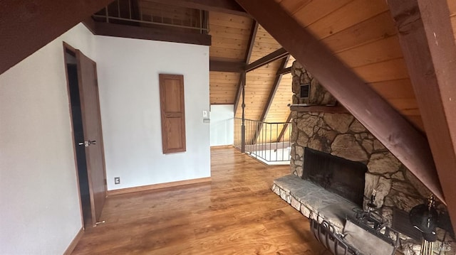 unfurnished living room with wooden ceiling, high vaulted ceiling, a stone fireplace, beam ceiling, and wood-type flooring