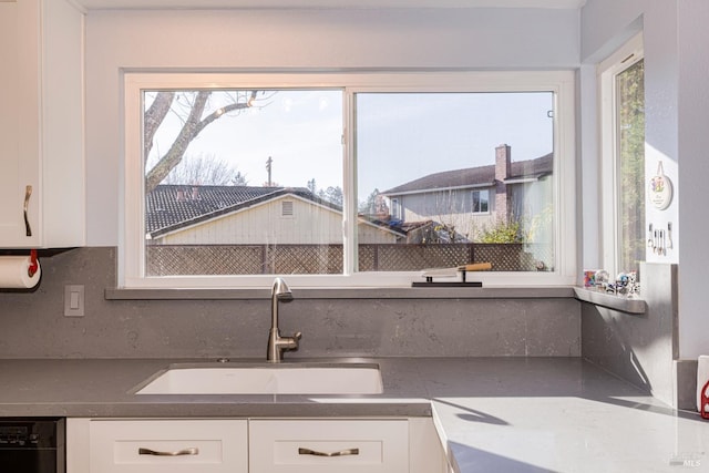 kitchen with white cabinets, decorative backsplash, black dishwasher, and sink