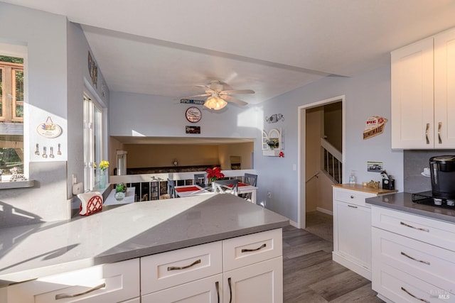 kitchen with kitchen peninsula, dark hardwood / wood-style floors, white cabinetry, and ceiling fan