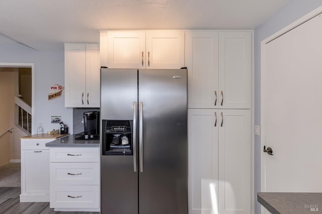 kitchen with white cabinets, a textured ceiling, stainless steel refrigerator with ice dispenser, and hardwood / wood-style floors