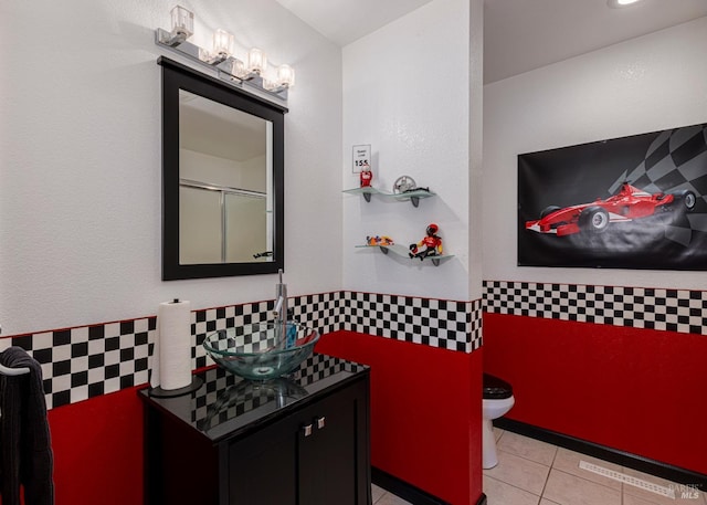 bathroom featuring tile patterned floors, vanity, toilet, and a shower with shower door