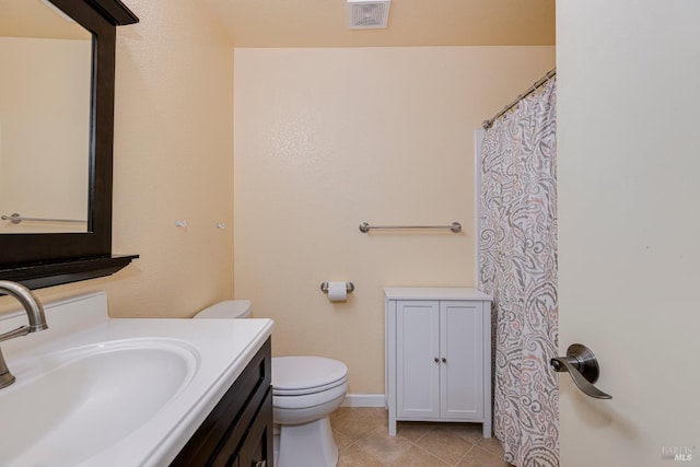 bathroom with toilet, vanity, and tile patterned floors