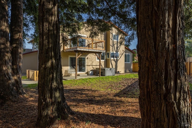 rear view of property with a balcony, central AC unit, a patio, and a hot tub