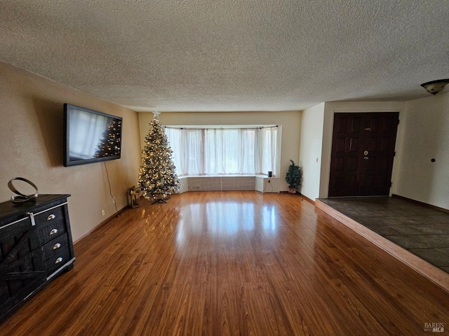 unfurnished living room featuring a textured ceiling and dark hardwood / wood-style flooring