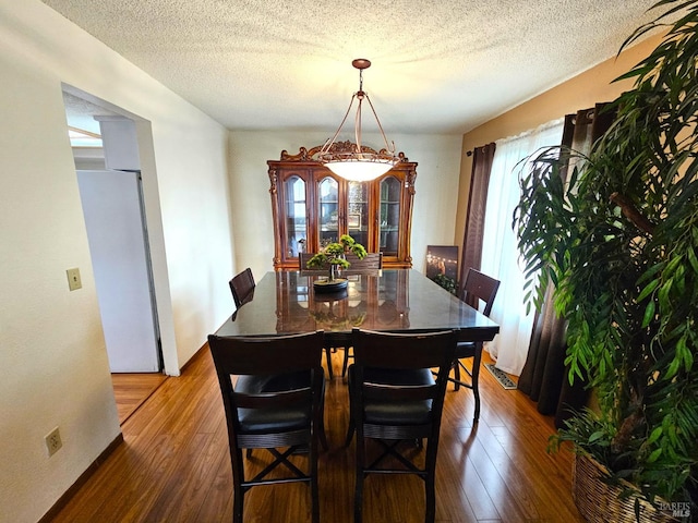 dining space featuring a textured ceiling and dark hardwood / wood-style floors