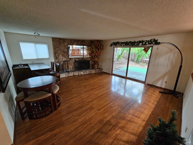 living room featuring hardwood / wood-style flooring, plenty of natural light, a fireplace, and a textured ceiling