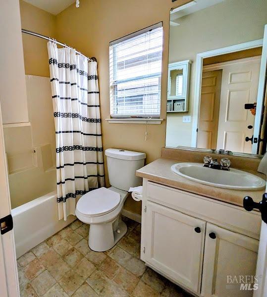 full bathroom featuring shower / tub combo with curtain, vanity, and toilet