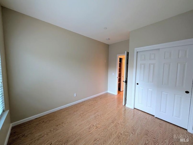 unfurnished bedroom featuring light hardwood / wood-style flooring and a closet