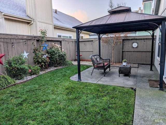 yard at dusk featuring a gazebo and a patio