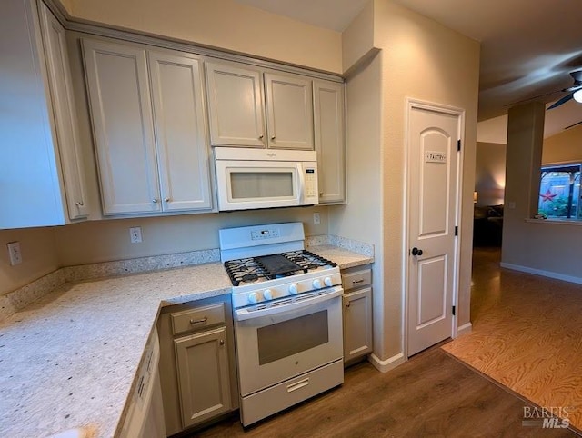 kitchen featuring light stone counters, white appliances, gray cabinets, and dark hardwood / wood-style floors