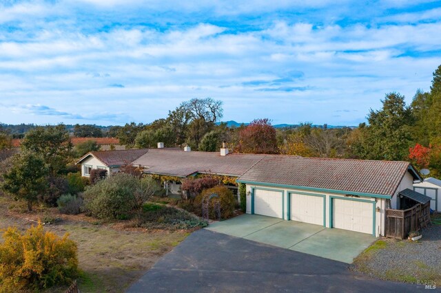 ranch-style house featuring a chimney, driveway, a tiled roof, and an attached garage