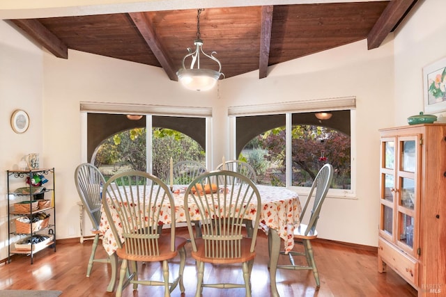 dining room featuring beamed ceiling, plenty of natural light, wood finished floors, and wood ceiling