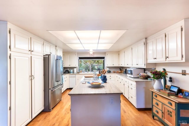 kitchen featuring white cabinets, light wood-style flooring, a kitchen island, high end fridge, and white microwave