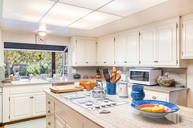 kitchen featuring white cabinets, white appliances, light countertops, and a sink