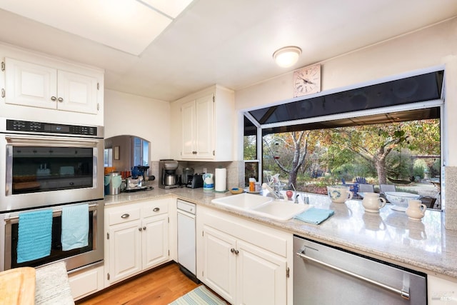 kitchen featuring light wood finished floors, a sink, white cabinets, and appliances with stainless steel finishes