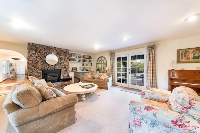 carpeted living area with french doors, a wood stove, and arched walkways