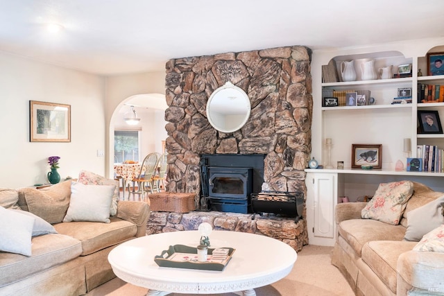 carpeted living room with a wood stove and arched walkways