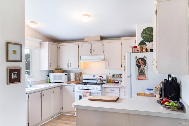 kitchen with a sink, white appliances, ventilation hood, a peninsula, and light countertops