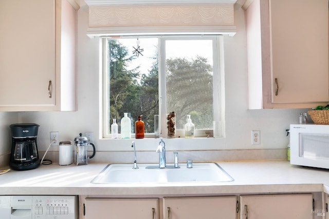 kitchen featuring white cabinetry, white appliances, light countertops, and a sink