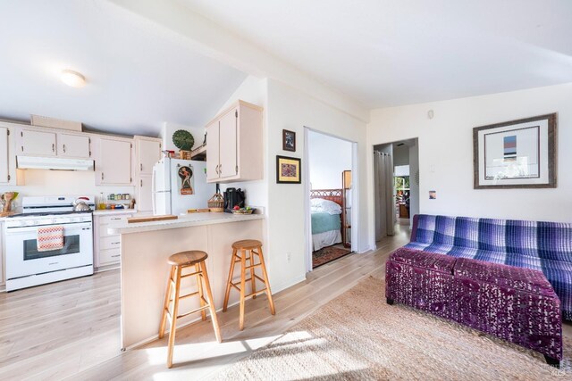 kitchen featuring white appliances, a kitchen bar, kitchen peninsula, and light wood-type flooring