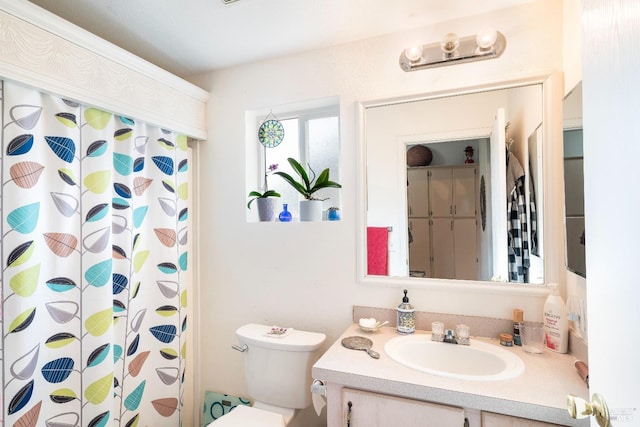 full bath featuring a shower with shower curtain, toilet, and vanity