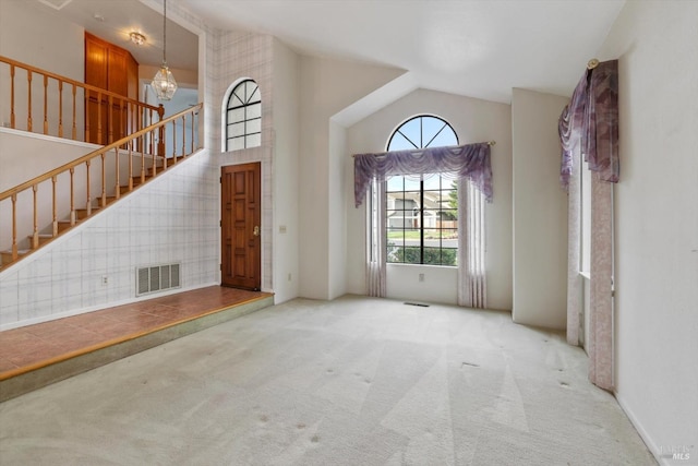 entrance foyer featuring light carpet, high vaulted ceiling, and an inviting chandelier