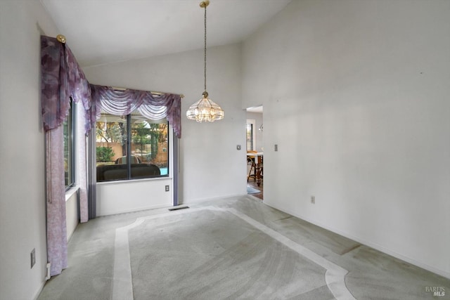 carpeted spare room with a notable chandelier and high vaulted ceiling