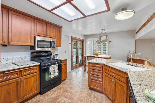 kitchen with light stone counters, sink, decorative light fixtures, and appliances with stainless steel finishes