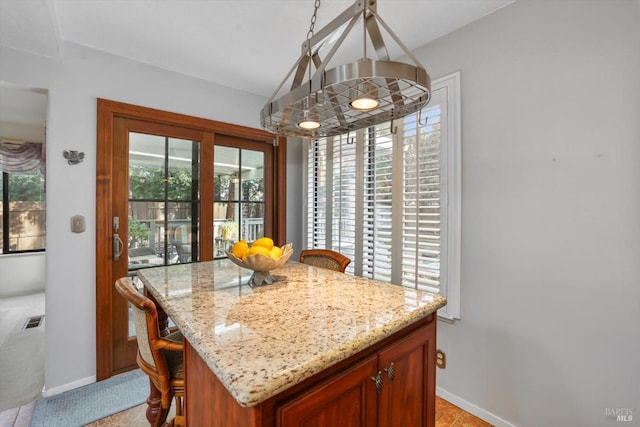 kitchen with light stone counters, a kitchen island, and light tile patterned flooring