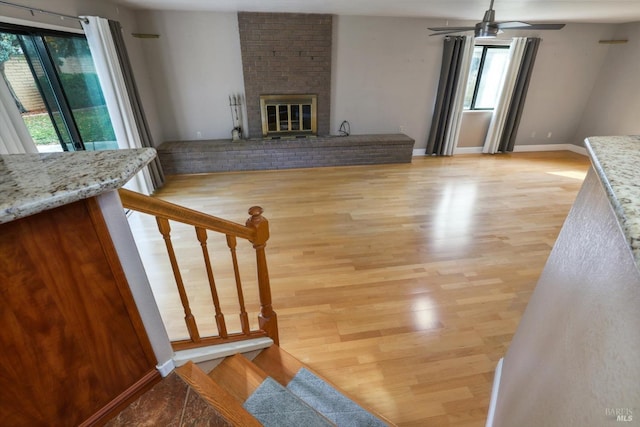 interior space with hardwood / wood-style floors, ceiling fan, and a brick fireplace