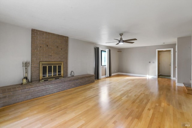 unfurnished living room featuring a brick fireplace, light hardwood / wood-style flooring, and ceiling fan