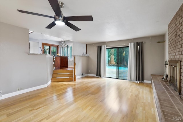 unfurnished living room with ceiling fan with notable chandelier and light wood-type flooring