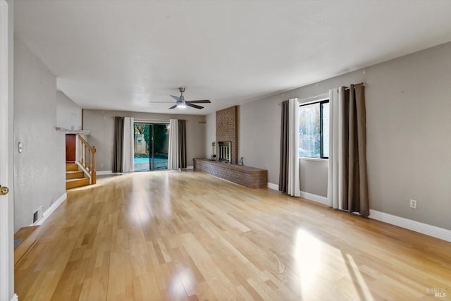 unfurnished living room with ceiling fan, light hardwood / wood-style flooring, and a brick fireplace