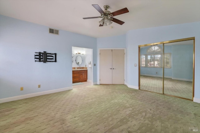 unfurnished bedroom with ceiling fan, light colored carpet, and ensuite bath