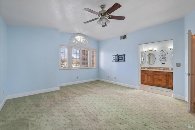 unfurnished bedroom featuring light carpet, connected bathroom, and ceiling fan