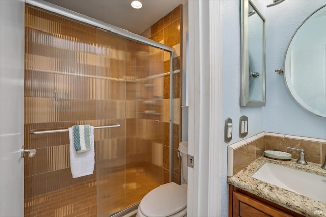 bathroom featuring vanity, an enclosed shower, and toilet