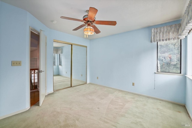 unfurnished bedroom featuring ceiling fan, light colored carpet, and a closet