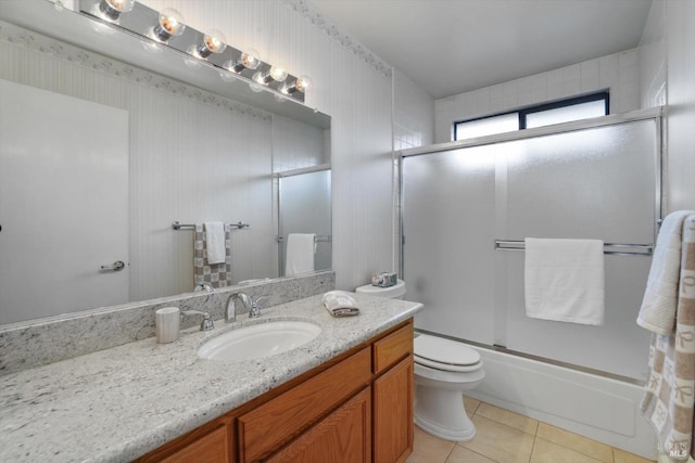 full bathroom with toilet, vanity, tile patterned floors, and bath / shower combo with glass door