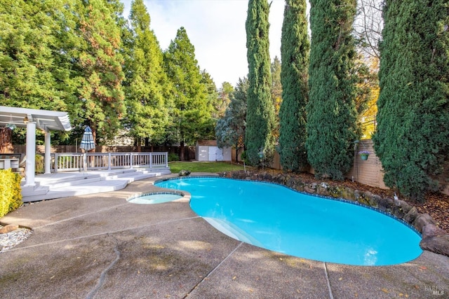 view of pool featuring a storage shed, a patio, and an in ground hot tub