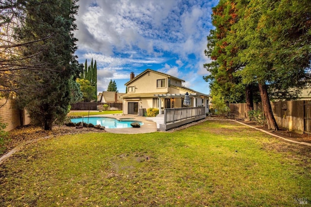 rear view of property with a yard and a pool side deck