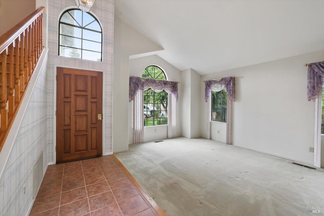 carpeted entrance foyer with high vaulted ceiling