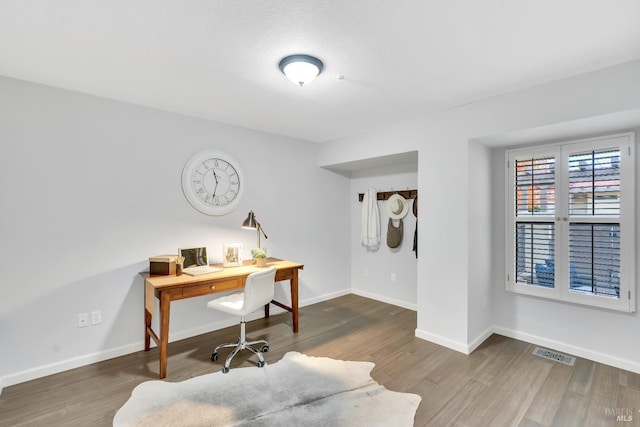 office space with wood finished floors, visible vents, and baseboards