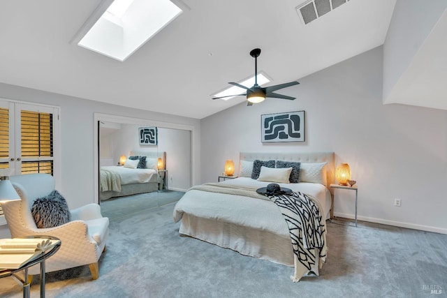 carpeted bedroom featuring visible vents, lofted ceiling with skylight, baseboards, and a ceiling fan